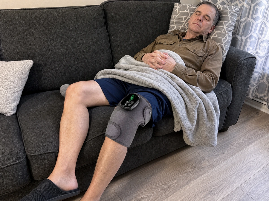 Older man resting at home while wearing the Revimus Motion red light heated knee massager